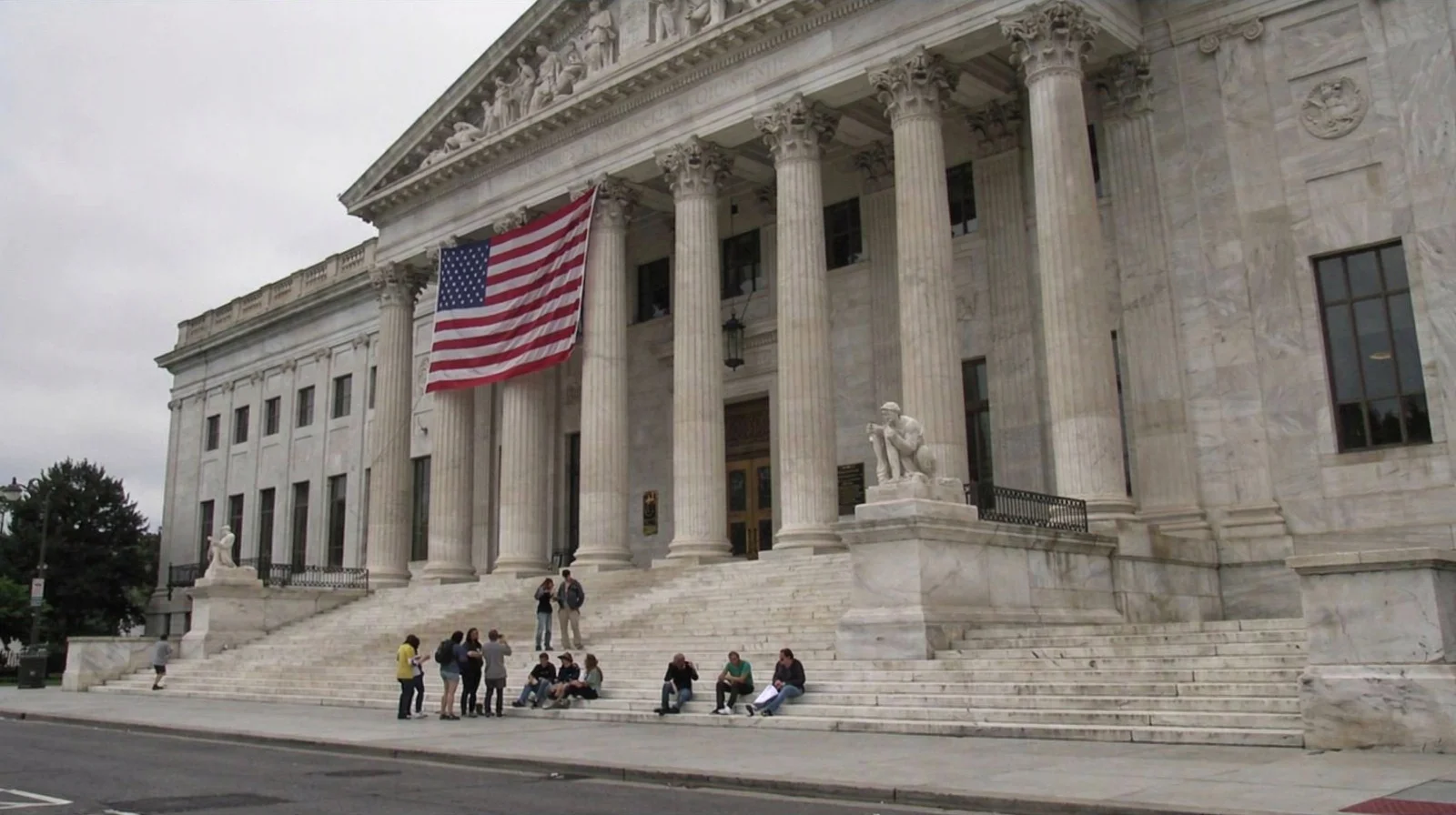 Limestone columns and steps of a federal Treasury building on an overcast day, tourists crossing the plaza