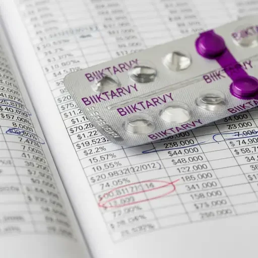 Close-up of Biktarvy blister pack against a ledger of drug pricing figures