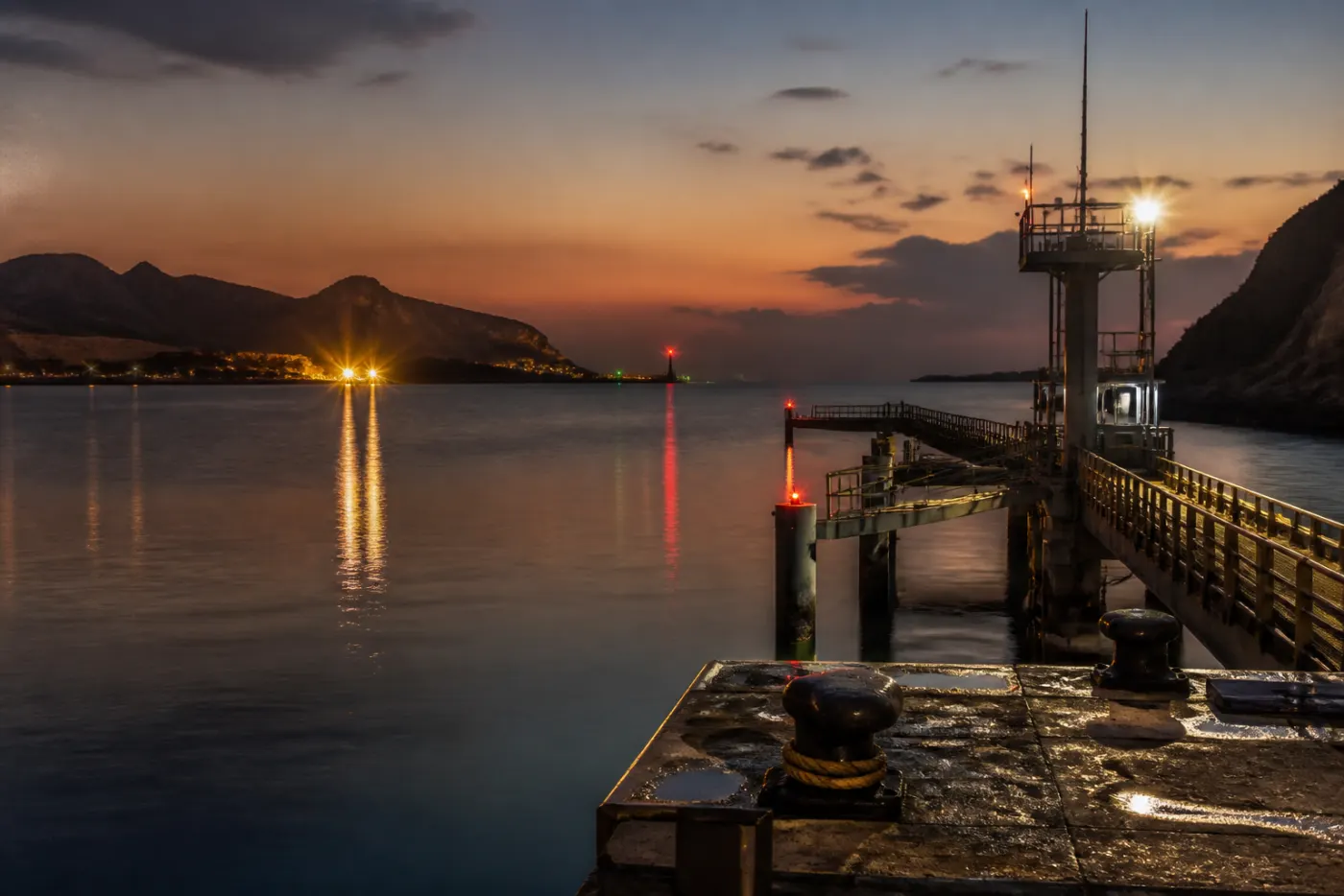 Empty pilot-boarding station at dusk on a Gulf jetty, navigation lights on the water, no queue of tankers