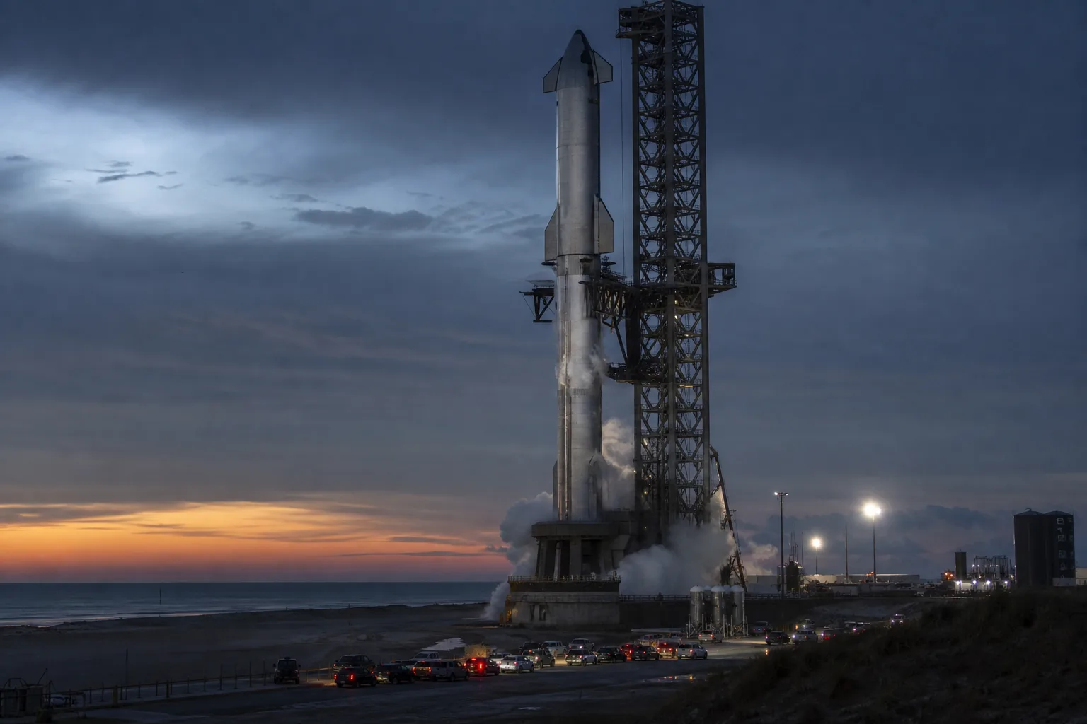 Stainless-steel heavy-lift rocket on a Gulf Coast pad at twilight as vapor vents ahead of a development test flight